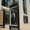 A worker unveils advertisement for future productions at the Metropolitan Opera.