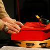 Stephin Merritt plays a toy piano, on top of a tambourine, with a mechanical toy bird.