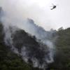 A Pakistani rescue helicopter flies over smoke and wreckage of a crashed passenger plane in The Margalla Hills on the outskirts of Islamabad on July 28, 2010.