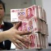 A Chinese bank worker arranges stacks of 100-yuan notes at a bank in Suining, southwest China's Sichuan province.