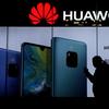A woman browses her smartphone as she walks by a Huawei store at a shopping mall in Beijing, Tuesday, Dec. 11, 2018.